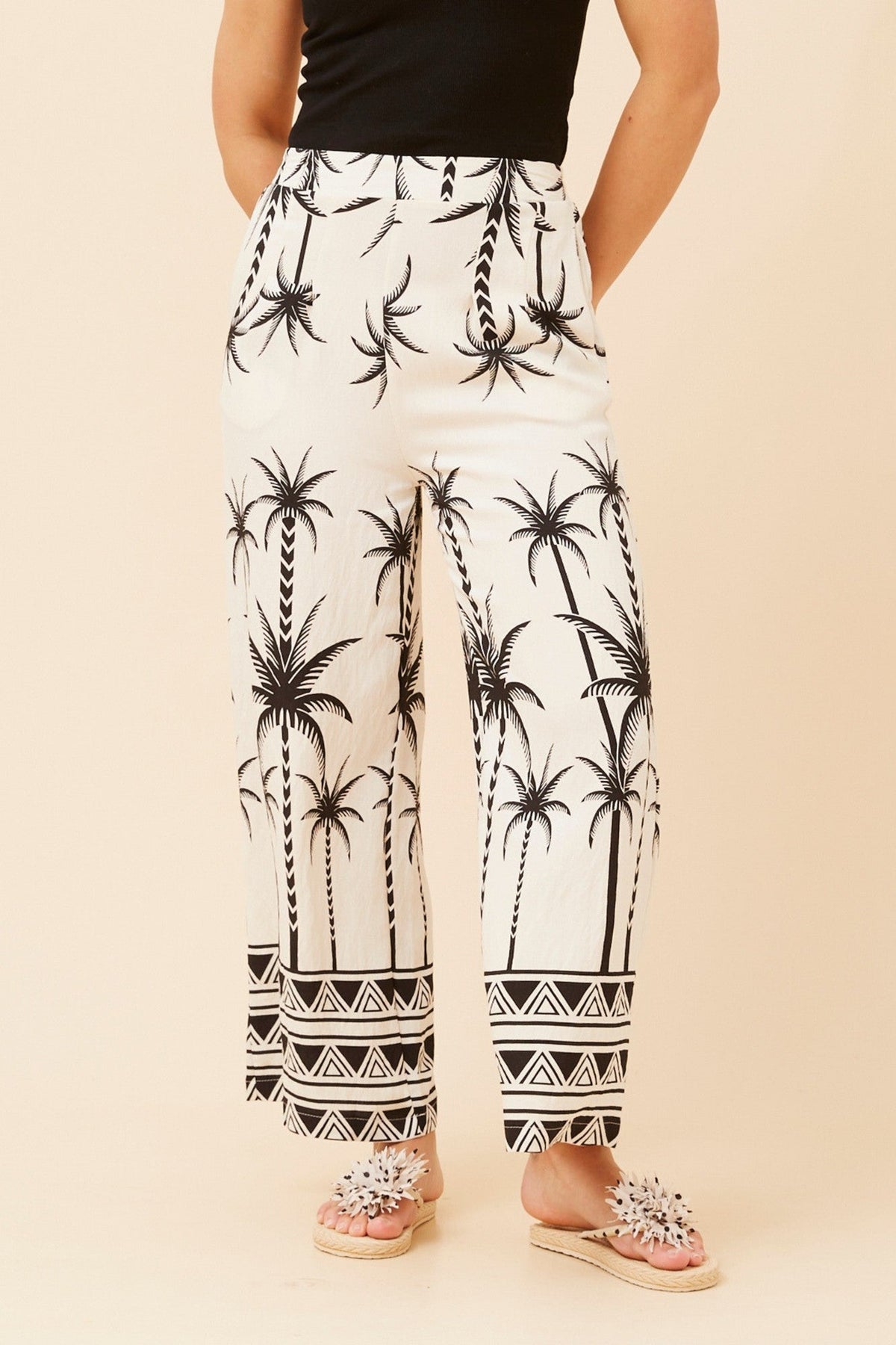 Image of a model wearing Pants. Product name - LOXANA PALM PRINT PANTS in Black colour by brand - Caroline Morgan Australia