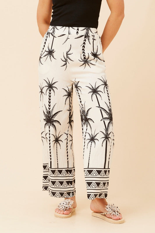 Image of a model wearing Pants. Product name - LOXANA PALM PRINT PANTS in Black colour by brand - Caroline Morgan Australia