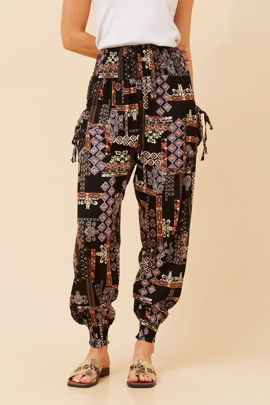 Image of a model wearing Pants. Product name - PATCHWORK PRINT HAREM PANTS in Multi Black colour by brand - Caroline Morgan Australia