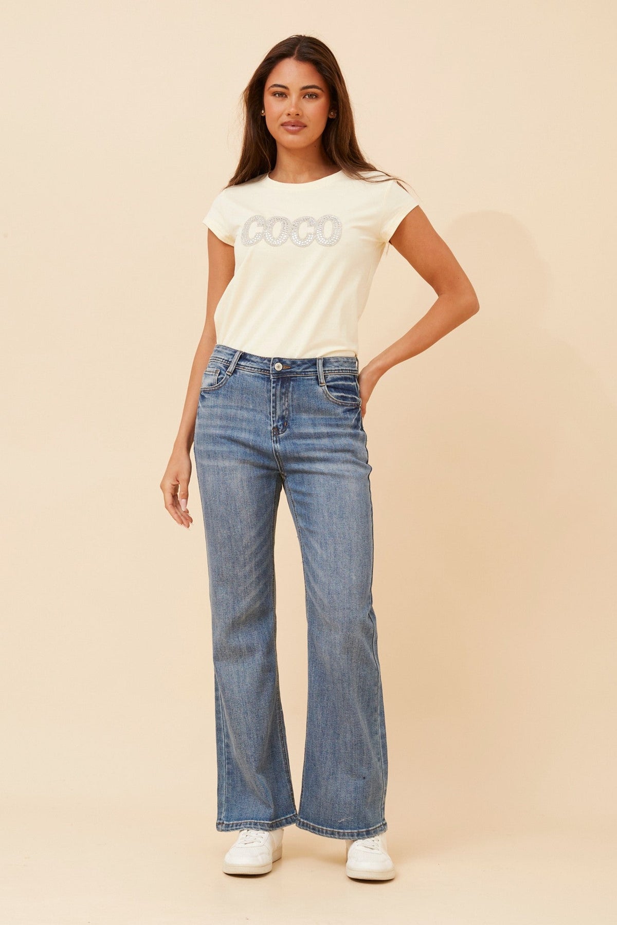Image of a model wearing Pants. Product name - DION FLARED LEG PANTS in Mid Denim colour by brand - INFINITY DENIM