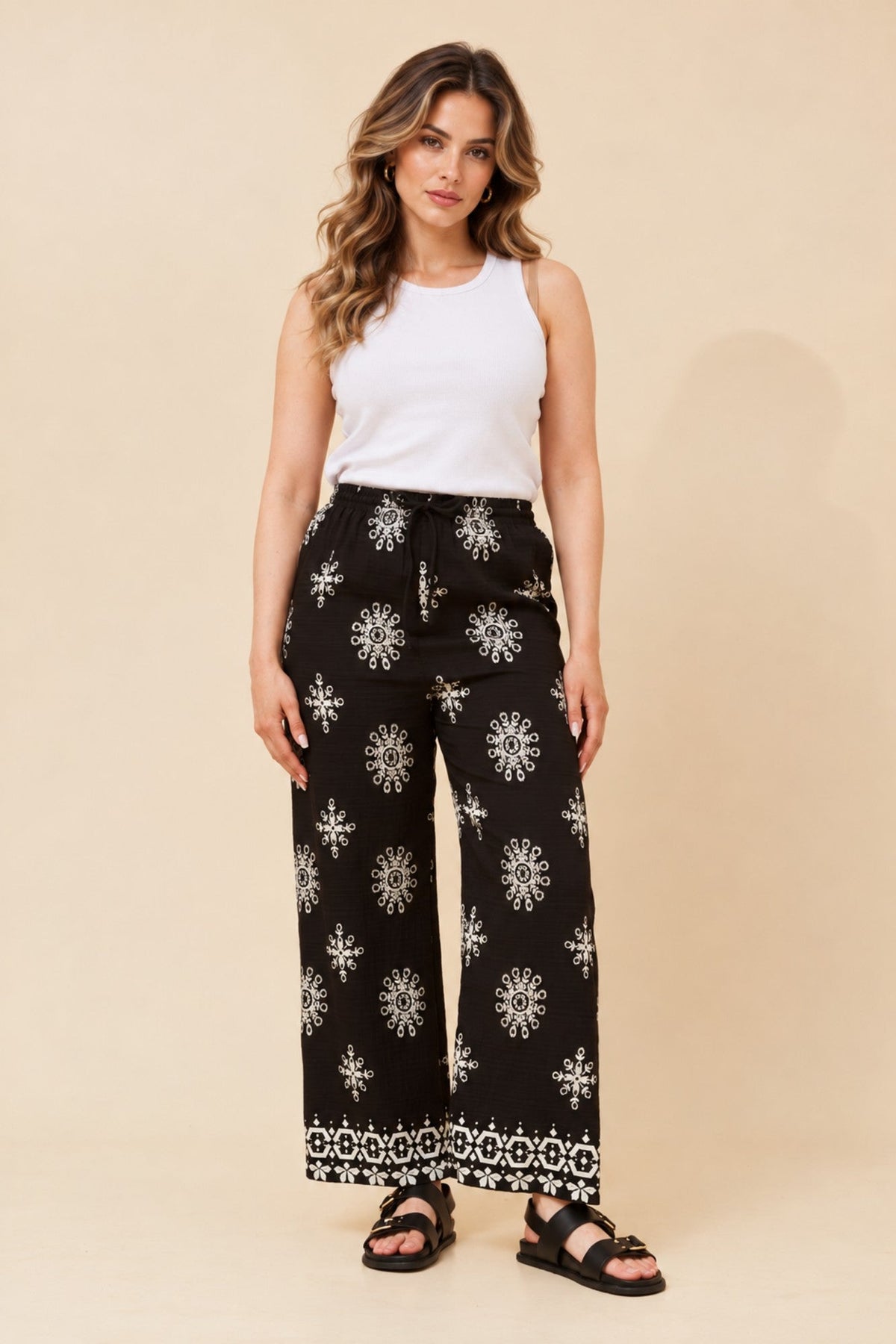 Image of a model wearing Pants. Product name - KARSYN EMBROIDERY PRINT PANTS in Black colour by brand - Caroline Morgan Australia