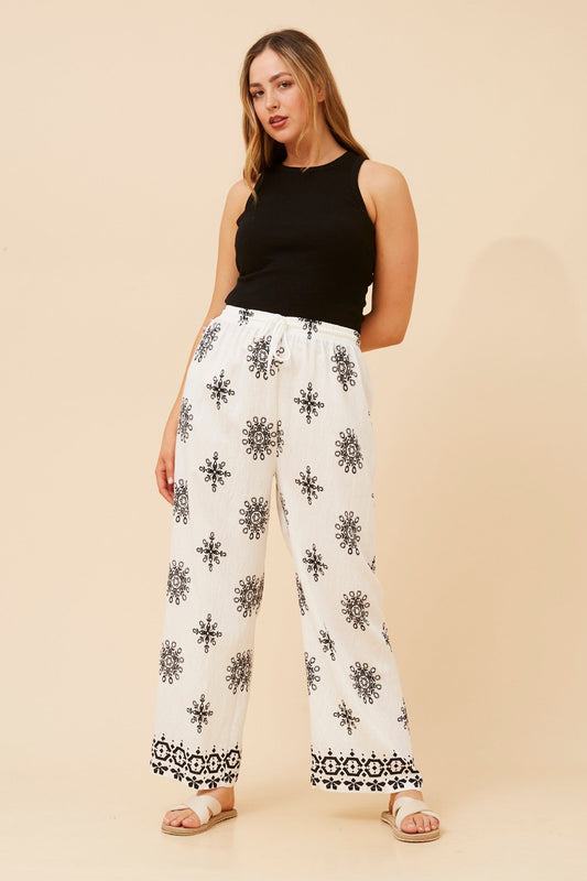 Image of a model wearing Pants. Product name - KARSYN EMBROIDERY PRINT PANTS in Black colour by brand - Caroline Morgan Australia
