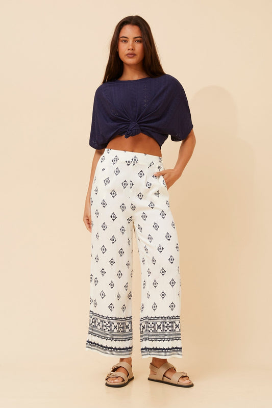 Image of a model wearing Pants. Product name - LOXANA BORDER PRINT WIDE LEG PANTS in Black/White colour by brand - Caroline Morgan Australia