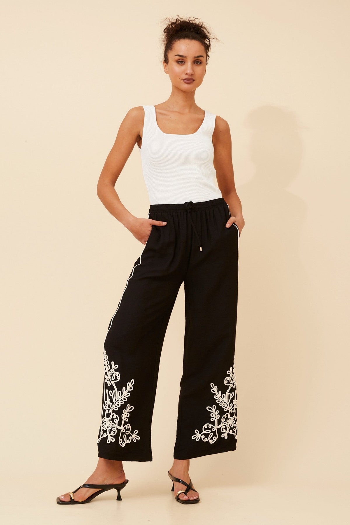Image of a model wearing Pants. Product name - OREN EMBROIDERED WIDE LEG PANTS in Black colour by brand - Caroline Morgan Australia