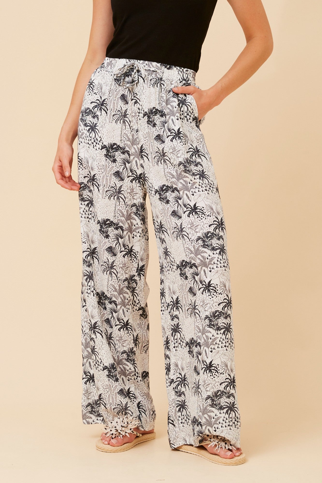 Image of a model wearing Pants. Product name - SUZZEL PALM TREE PRINT PANTS in Rust colour by brand - Caroline Morgan Australia