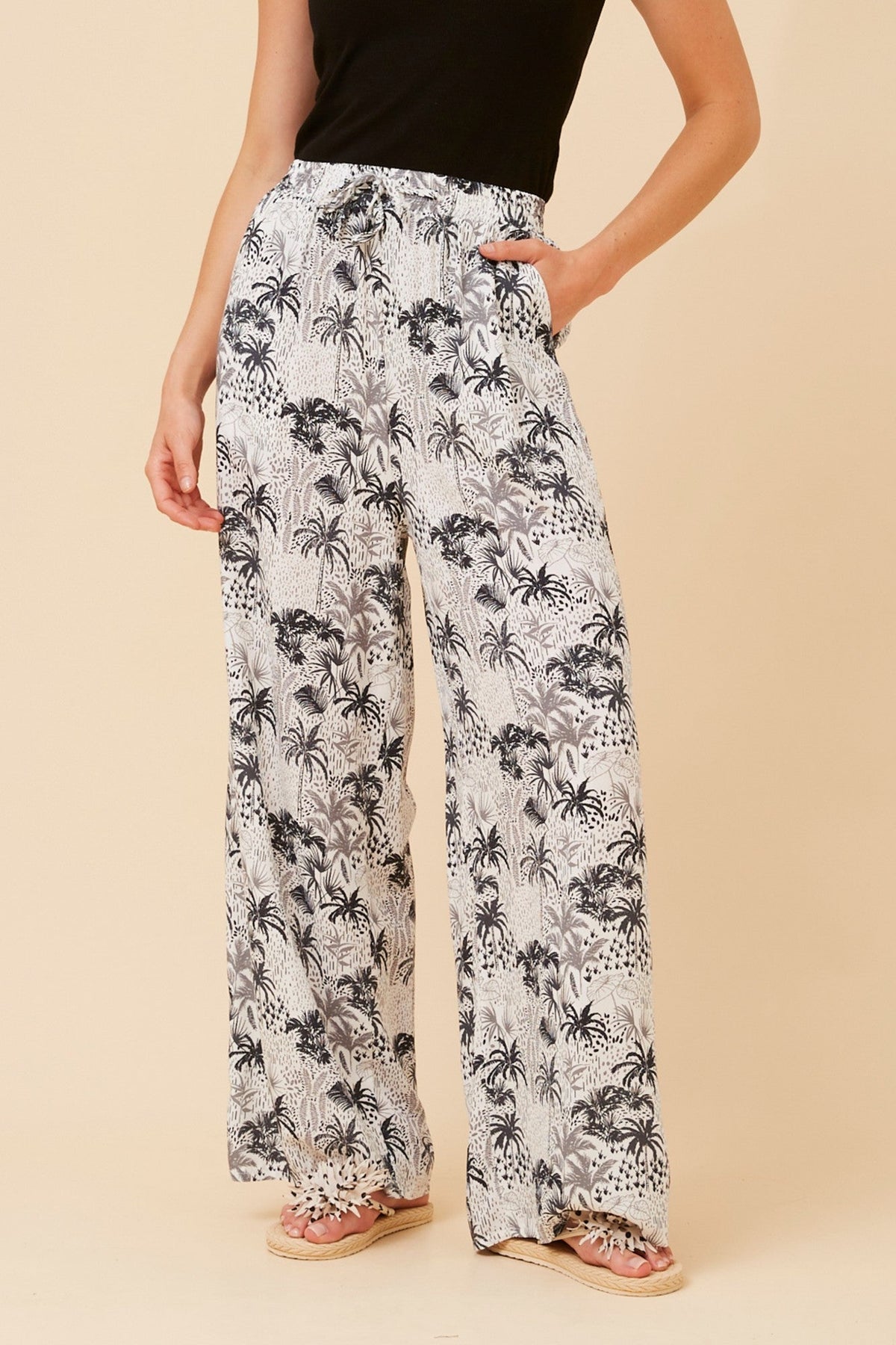 Image of a model wearing Pants. Product name - SUZZEL PALM TREE PRINT PANTS in Rust colour by brand - Caroline Morgan Australia