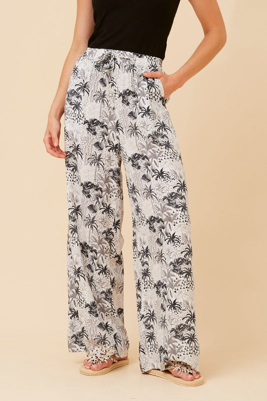 Image of a model wearing Pants. Product name - SUZZEL PALM TREE PRINT PANTS in Rust colour by brand - Caroline Morgan Australia