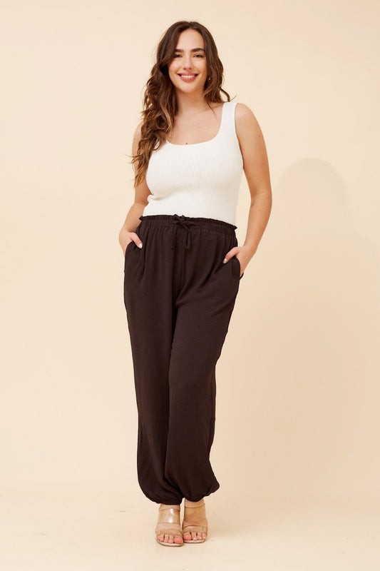 Image of a model wearing Pants. Product name - LEWIS SOLID JOGGER PANTS in Chocolate colour by brand - Caroline Morgan Australia