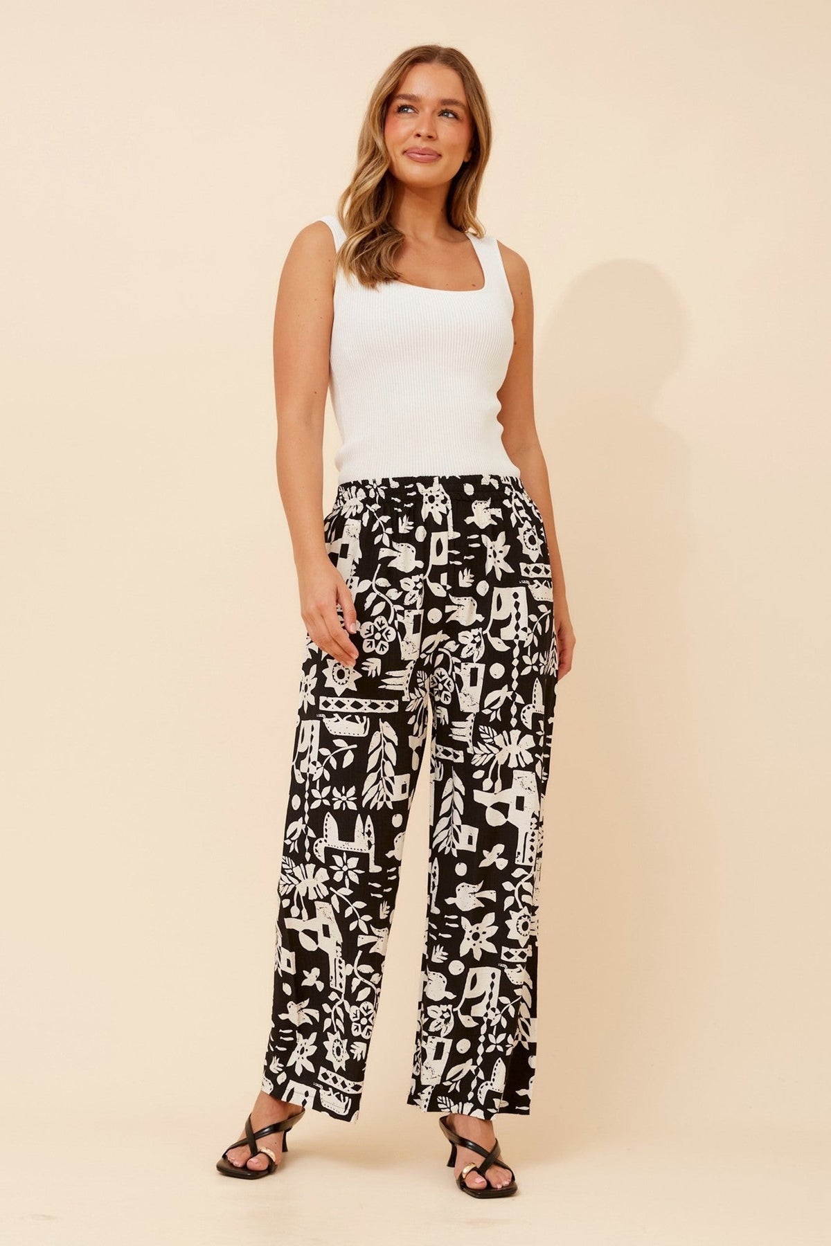 Image of a model wearing Pants. Product name - YULENKA WANDERLUST PRINT PANTS in Black/Cream colour by brand - Caroline Morgan Australia