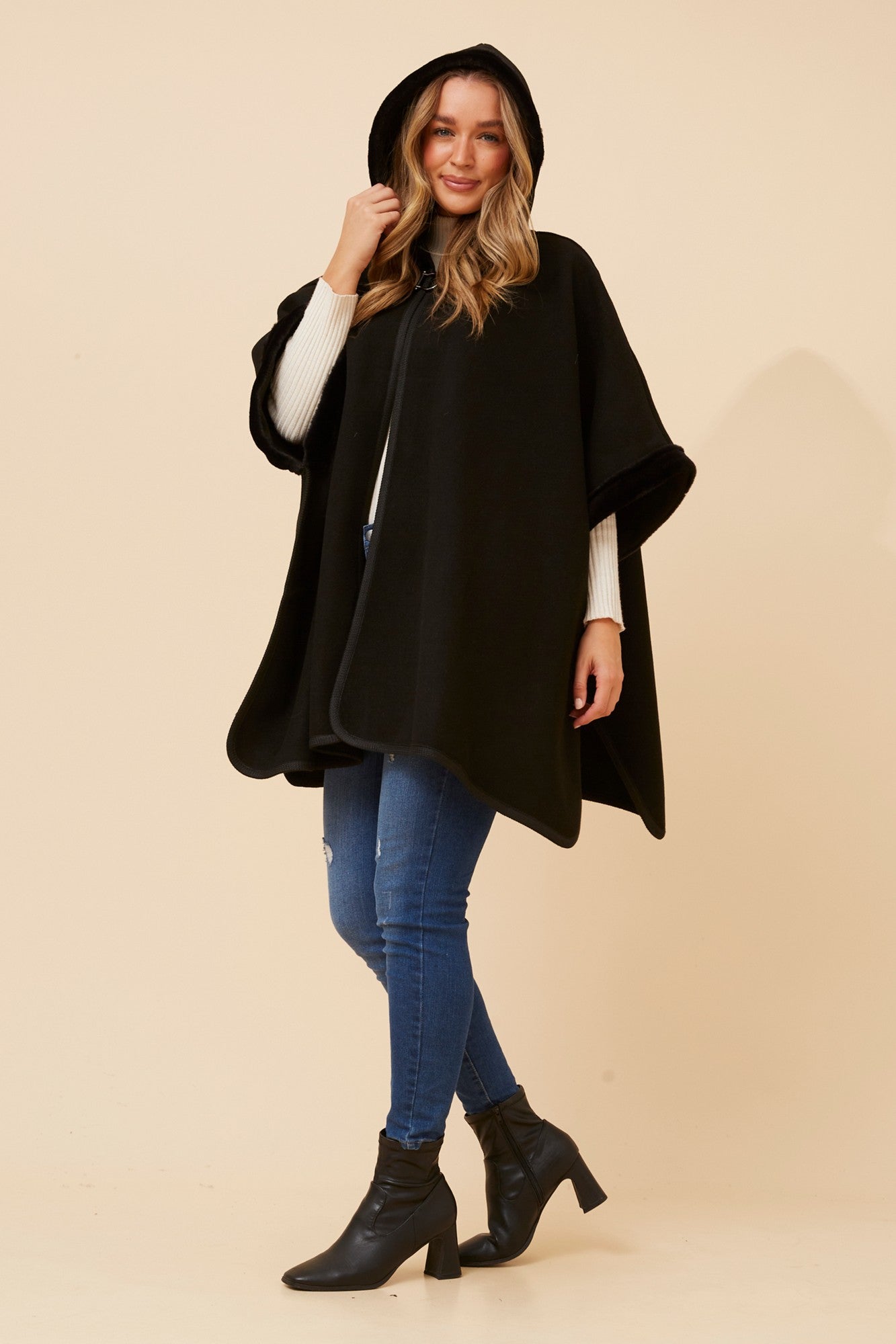 Image of a model wearing Outerwear. Product name - AMBERLYN SOLID PONCHO in Black colour by brand - Caroline Morgan Australia