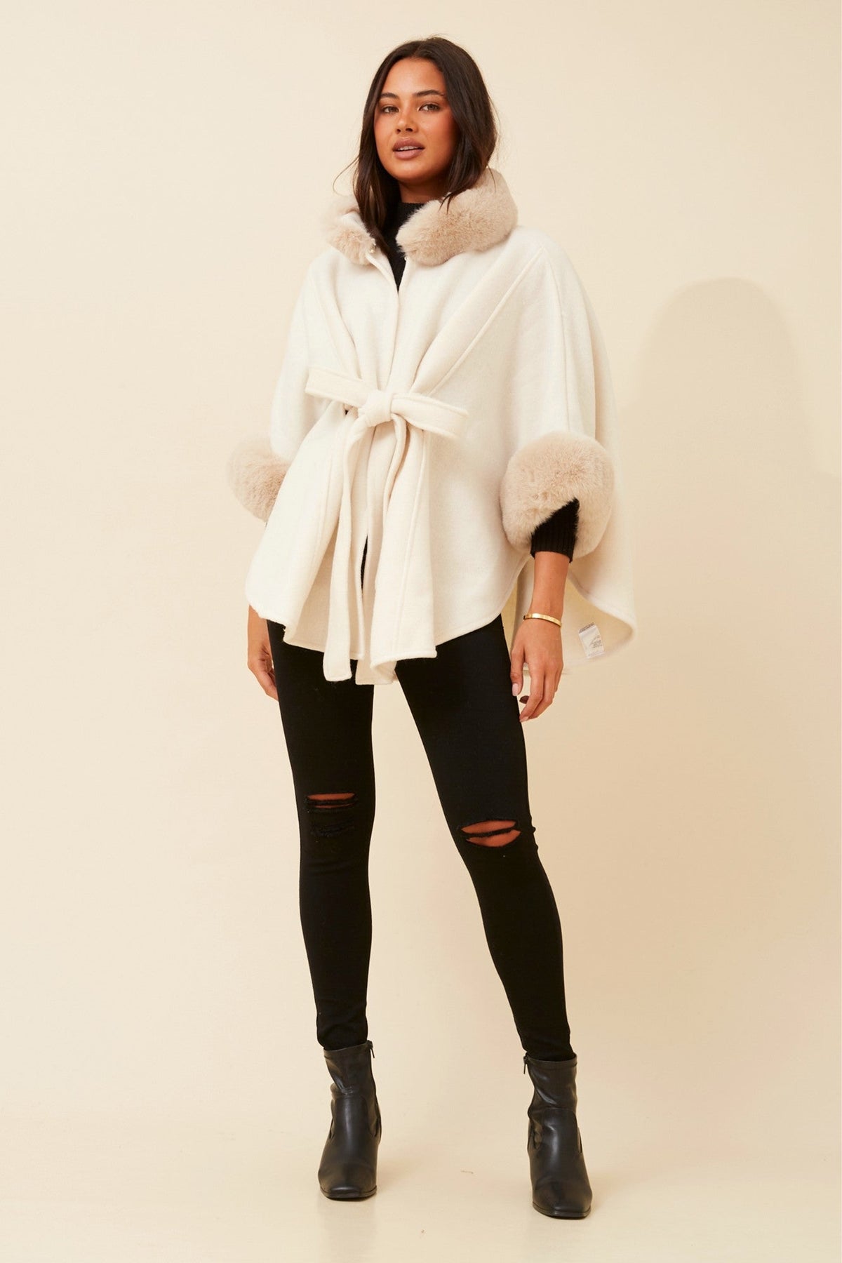 Image of a model wearing Outerwear. Product name - RYLAN FAUX FUR TRIM PONCHO in Black colour by brand - Caroline Morgan Australia