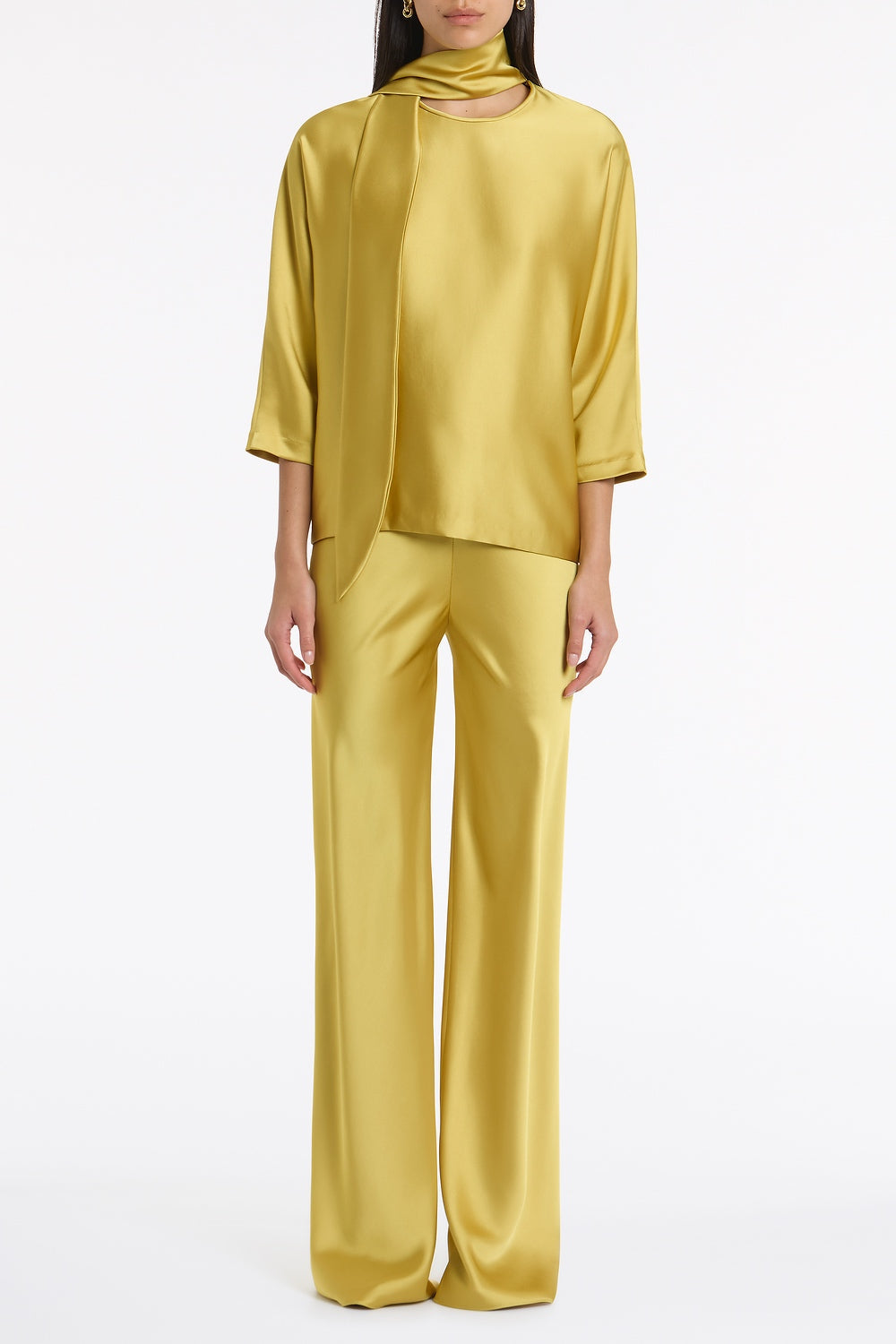 Image of a model wearing Tops. Product name - Pear Lustre Satin Tie Neck Blouse in Green colour by brand - Carla Zampatti