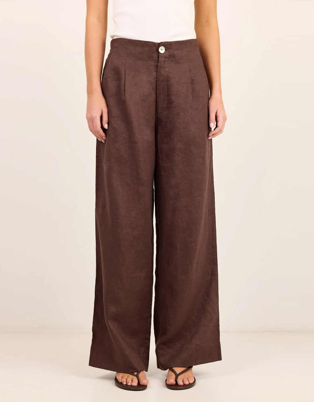 Image of a model wearing Pants. Product name - Curator Linen Pleat Front Wide Leg Pants Dark Chocolate in Dark Chocolate colour by brand - Re:Union The Label