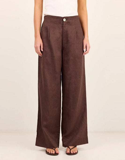 Image of a model wearing Pants. Product name - Curator Linen Pleat Front Wide Leg Pants Dark Chocolate in Dark Chocolate colour by brand - Re:Union The Label