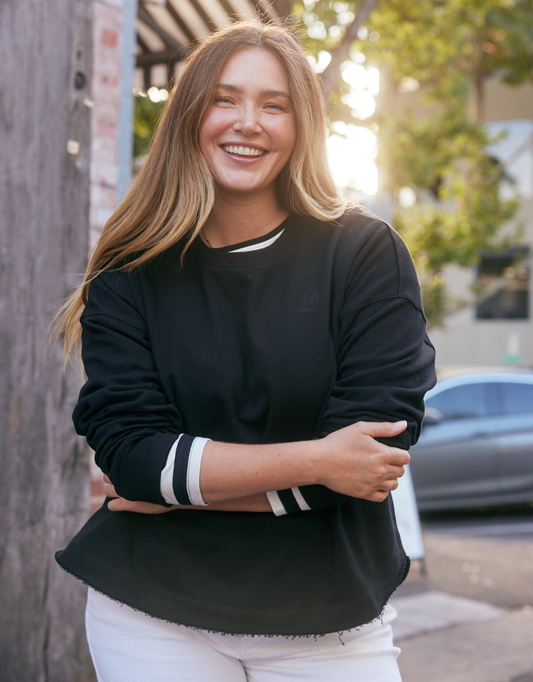 Image of a model wearing Outerwear. Product name - Staple Scoop Hem Sweat Black in Black colour by brand - White & Co.