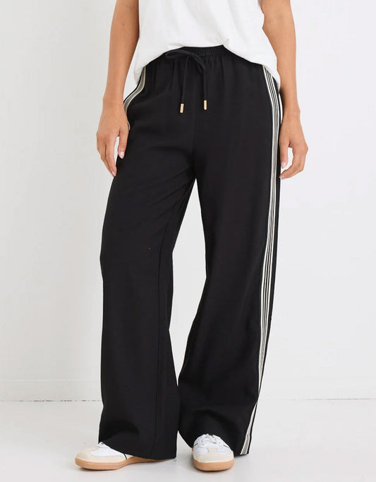 Image of a model wearing Pants. Product name - Vibe Jacquard Stripe Wide Leg Pants Black in Black colour by brand - Stories Be Told
