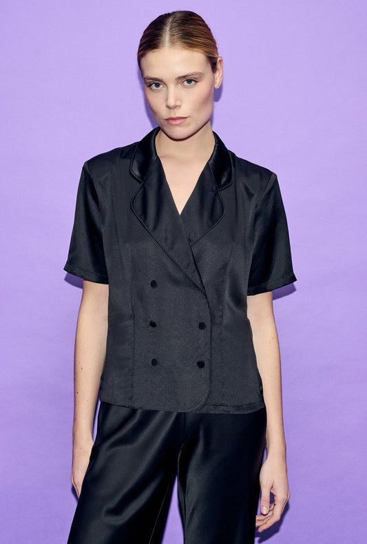Image of a model wearing Tops. Product name - Short Sleeve Double Breasted Jacket in Black Satin colour by brand - Silk Laundry