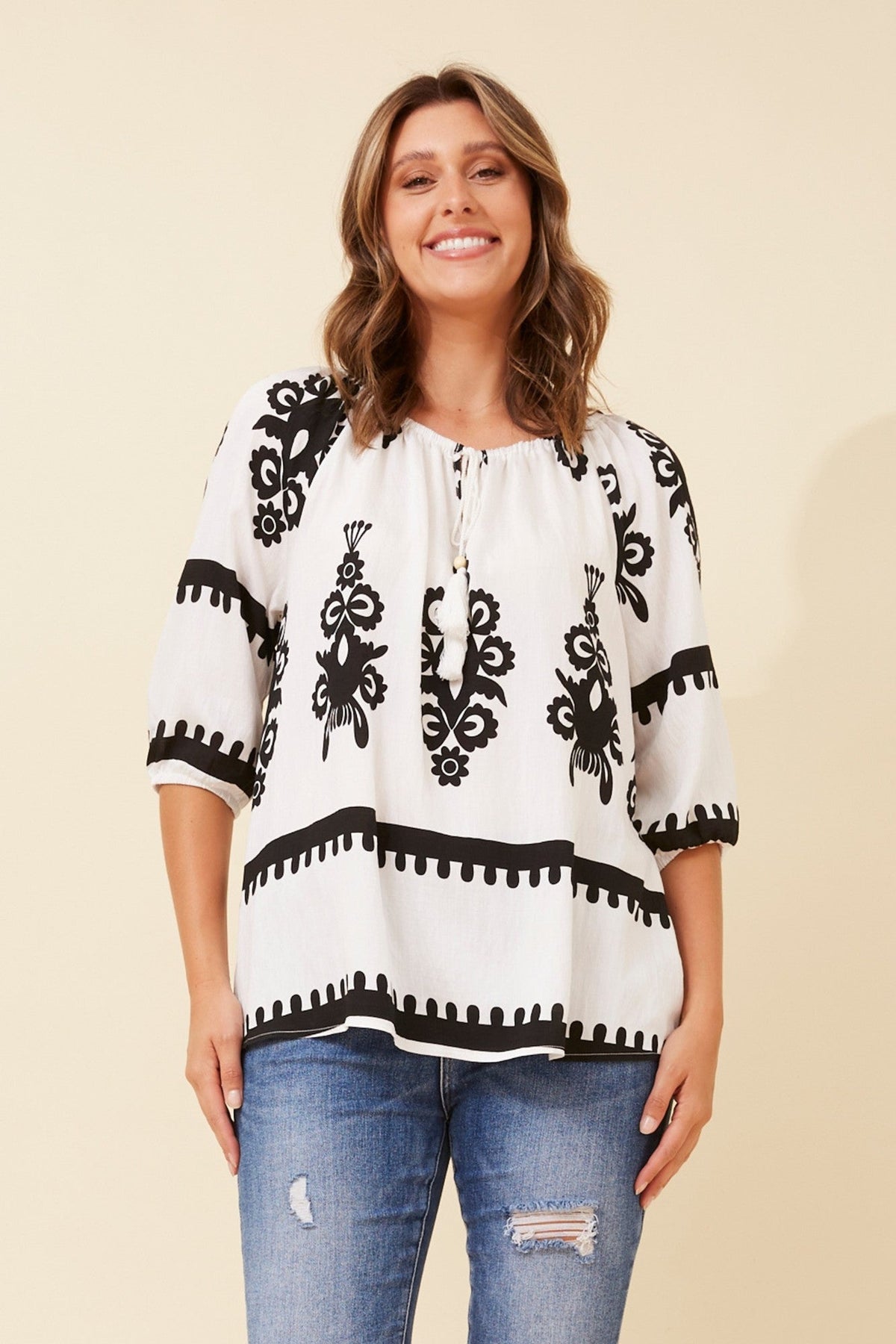 Image of a model wearing Tops. Product name - ANDREA BORDER PRINT TOP in White colour by brand - Caroline Morgan Australia