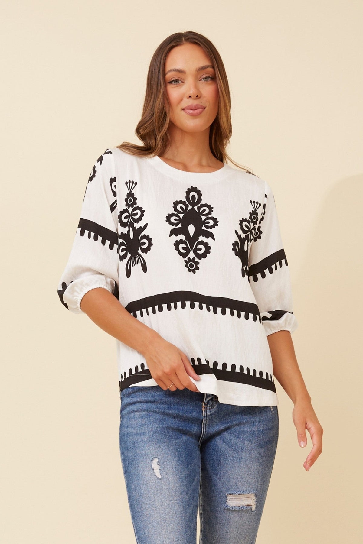 Image of a model wearing Tops. Product name - SHAE BORDER PRINT TOP in White colour by brand - Caroline Morgan Australia