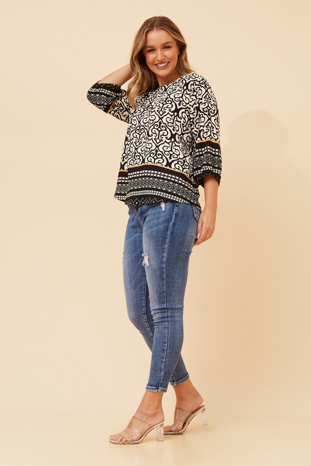 Image of a model wearing Tops. Product name - SHAE BORDER PRINT TOP in Black colour by brand - Caroline Morgan Australia