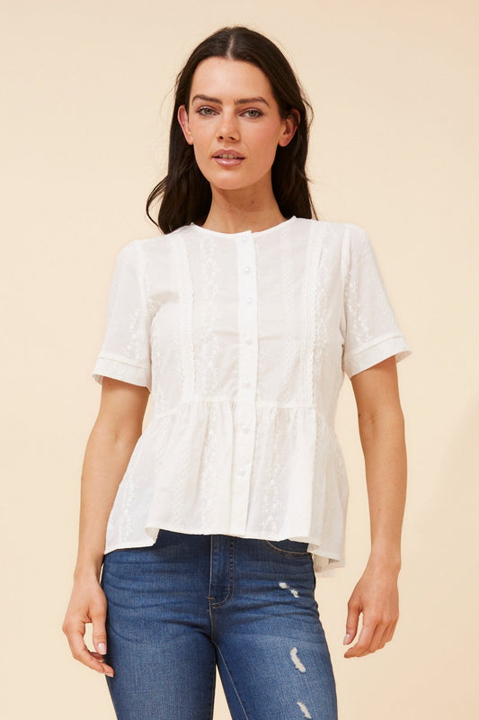 Image of a model wearing Tops. Product name - ANICA EMBROIDERED PEPLUM TOP in White colour by brand - Caroline Morgan Australia