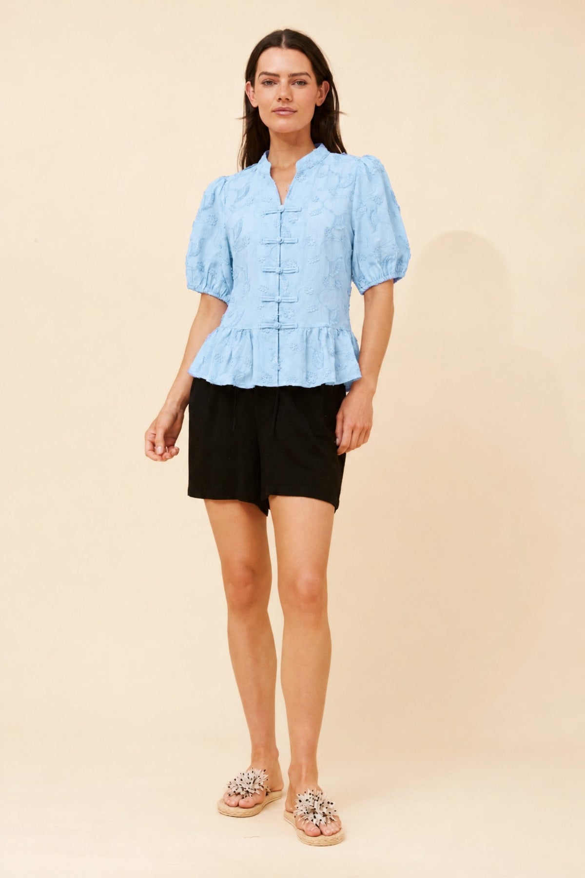 Image of a model wearing Tops. Product name - WITLEE EMBROIDERED PEPLUM TOP in Blue colour by brand - Caroline Morgan Australia