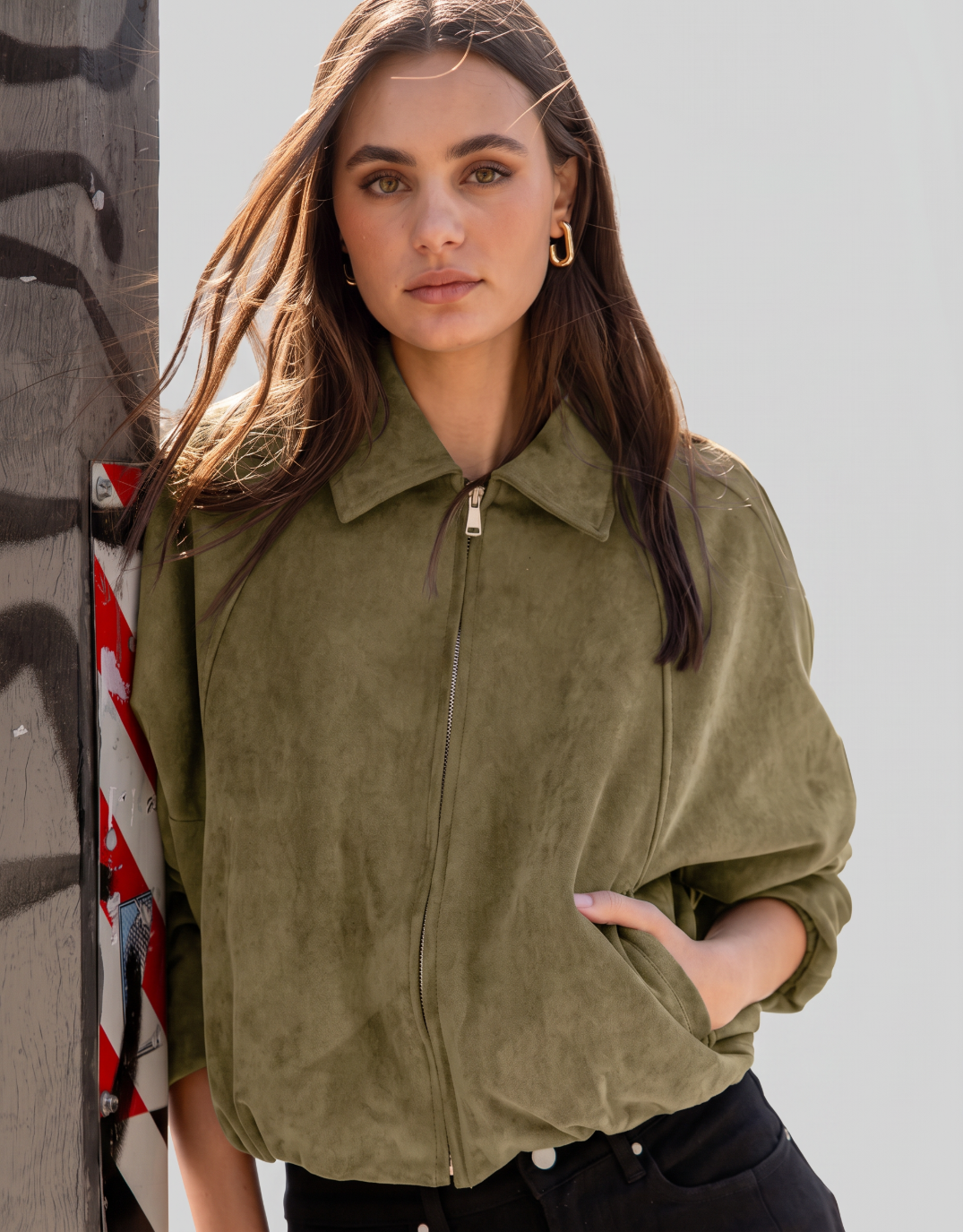 Image of a model wearing Outerwear. Product name - Troupe Faux Suede Zip Through Bubble Hem Bomber Jacket Khaki in Khaki colour by brand - Stories Be Told