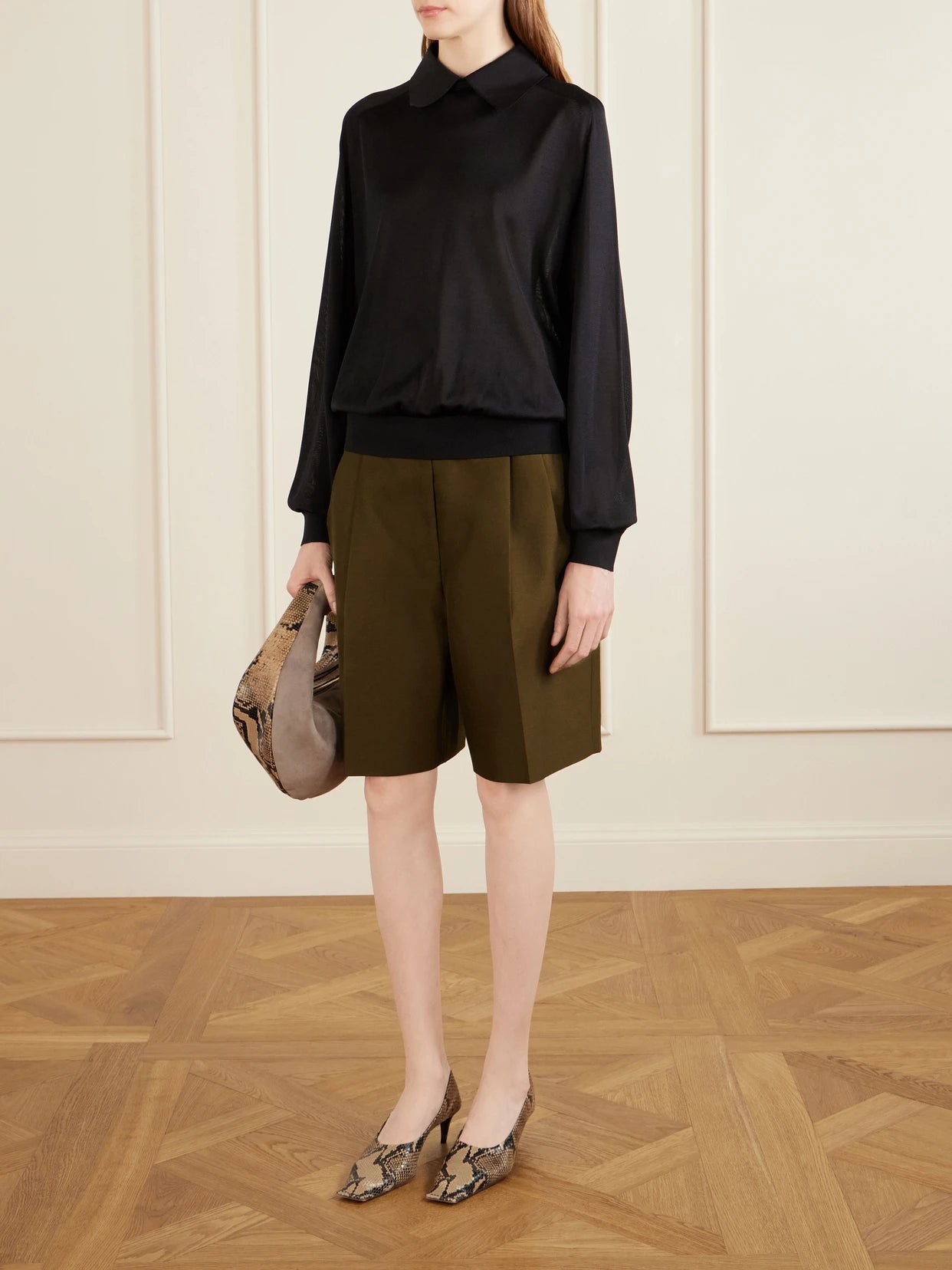 Image of a model wearing Outerwear. Product name - Alexa Silk-knitted Polo Sweater in Black colour by brand - KHAITE