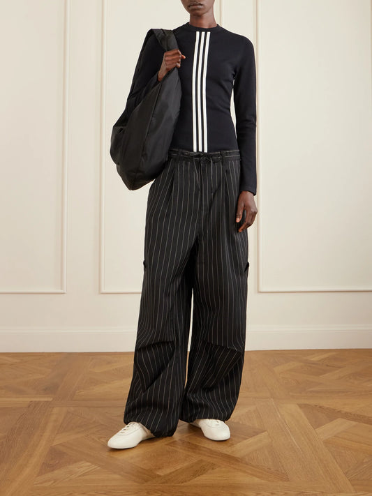 Image of a model wearing Pants. Product name - + Y-3 Pinstriped Recycled Woven Wide-leg Pants in Black colour by brand - adidas Originals