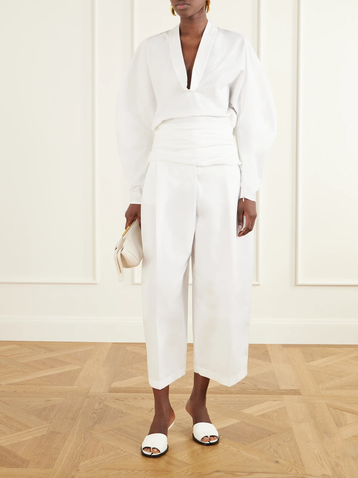 Image of a model wearing Pants. Product name - Miami Cotton Tapered Pants in White colour by brand - Jacquemus
