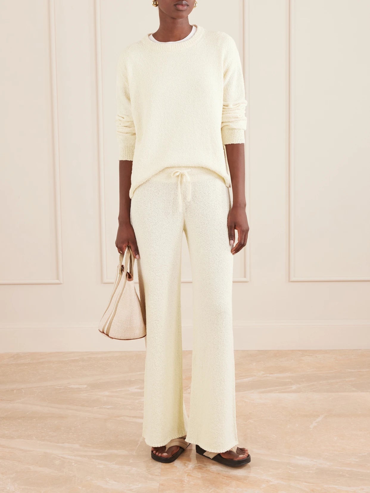 Image of a model wearing Pants. Product name - Calla Cotton-bouclé Flared Pants in Ecru colour by brand - Suzie Kondi
