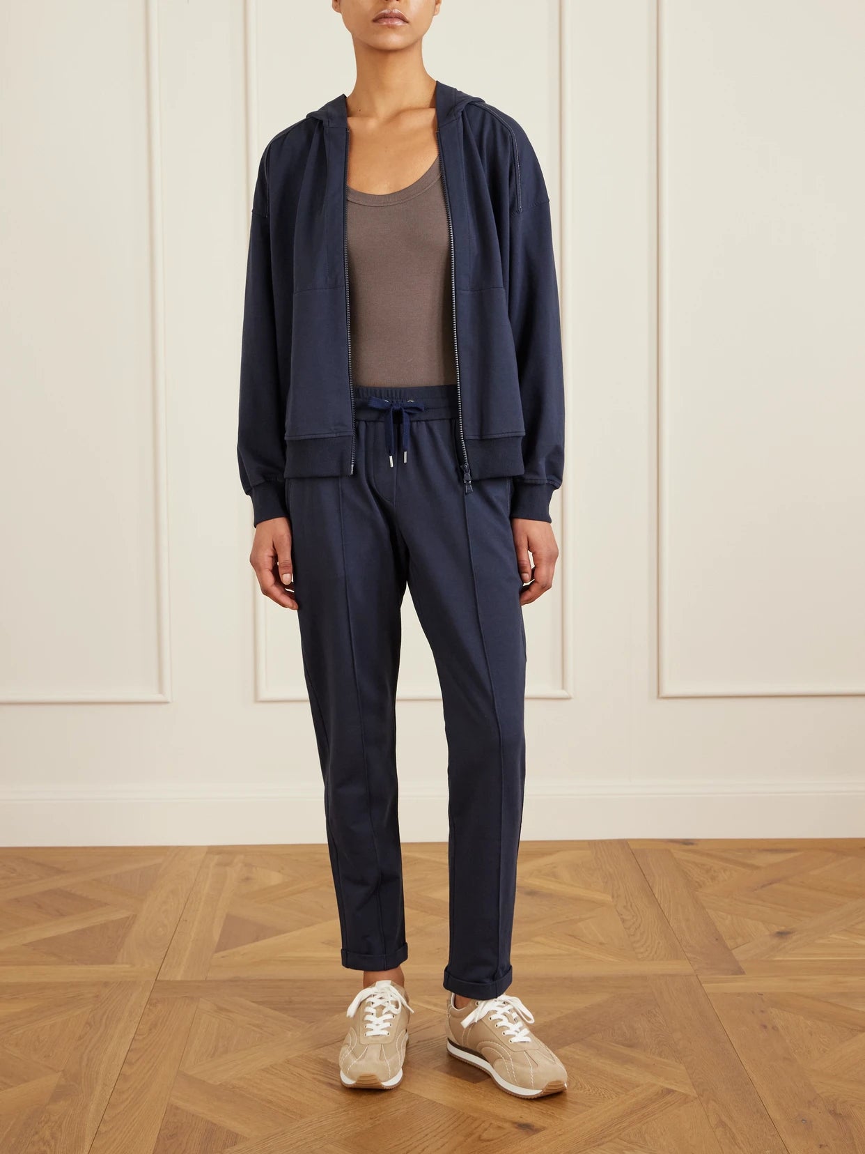 Image of a model wearing Tops. Product name - Bead-embellished Cotton-blend Jersey Track Pants in Navy colour by brand - Brunello Cucinelli