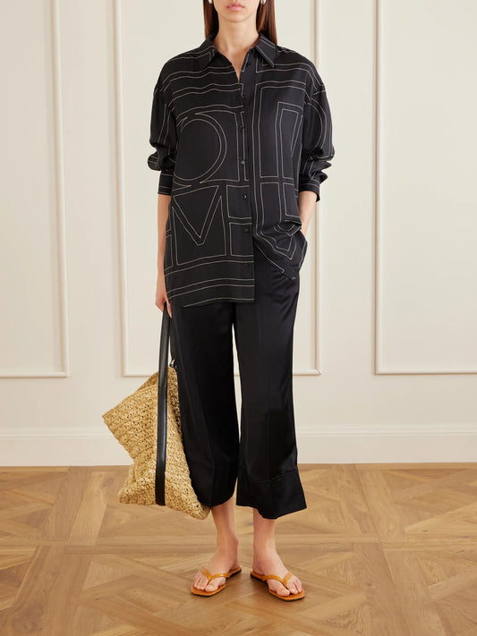 Image of a model wearing Tops. Product name - Embroidered Silk-twill Shirt in Black colour by brand - TOTEME