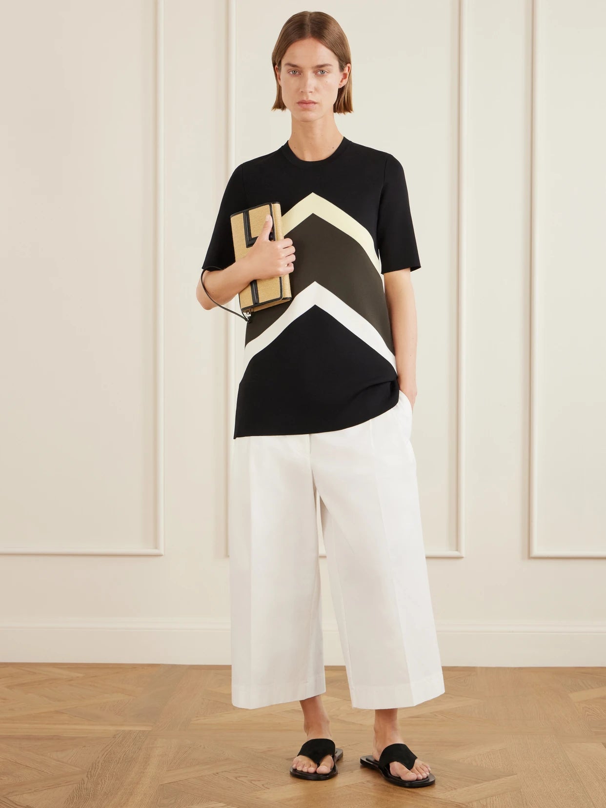 Image of a model wearing Pants. Product name - Cropped Pleated Organic Cotton And Lyocell-blend Straight-leg Pants in White colour by brand - TOTEME