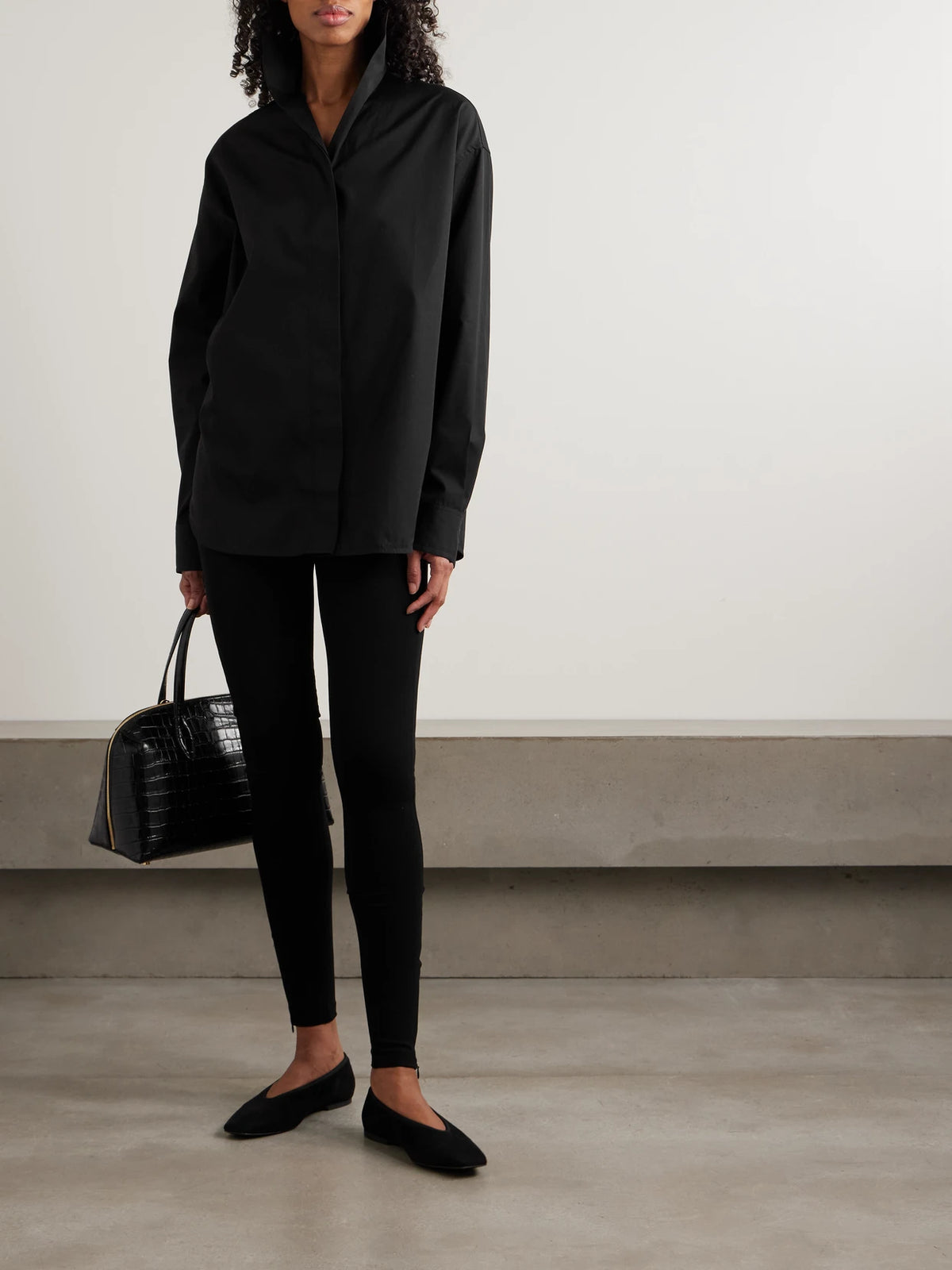 Image of a model wearing Tops. Product name - Sharp Oversized Cotton-poplin Shirt in Black colour by brand - TOTEME