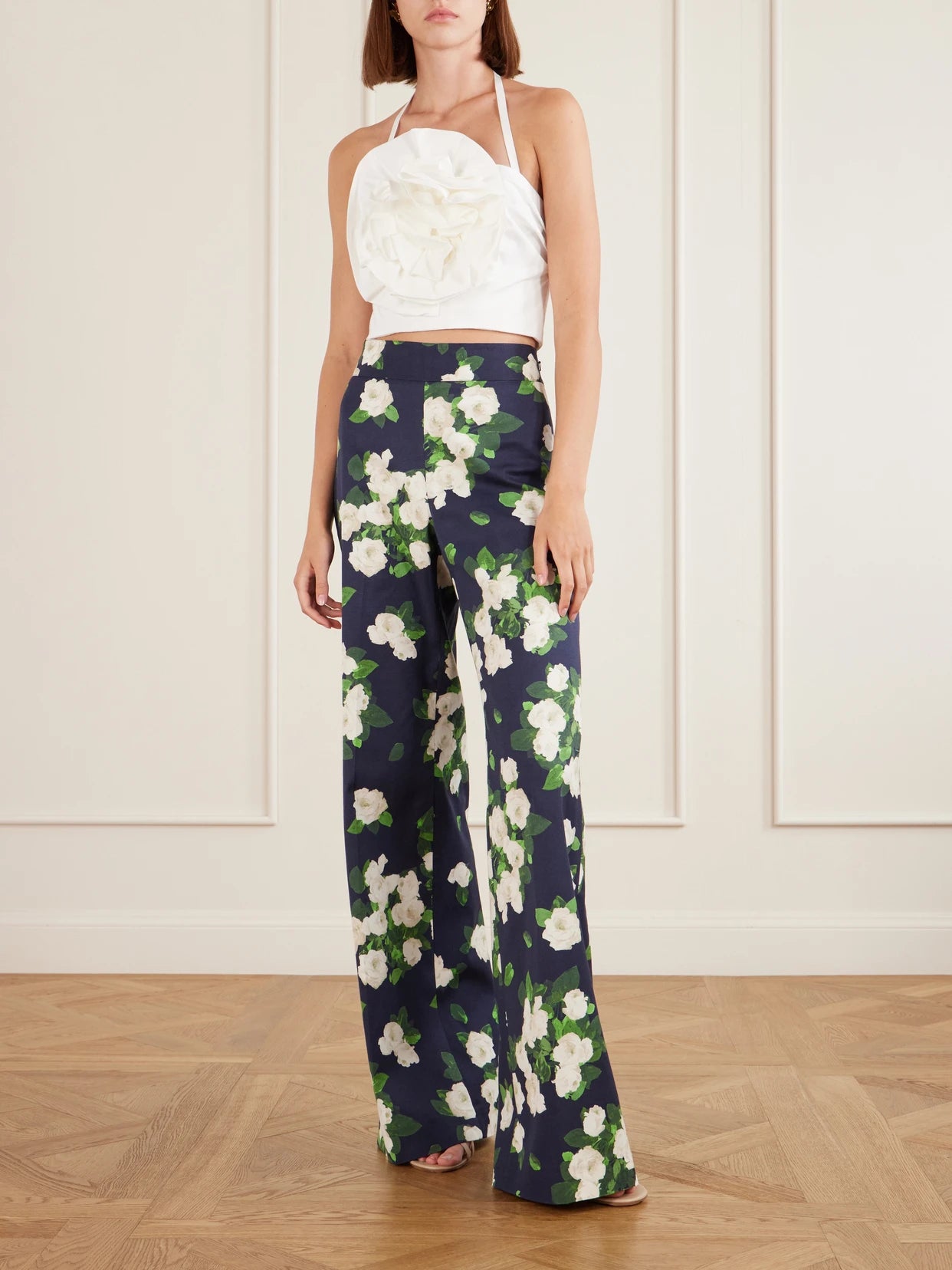 Image of a model wearing Tops. Product name - Floral-appliquéd Cotton-blend Halterneck Top in White colour by brand - Carolina Herrera
