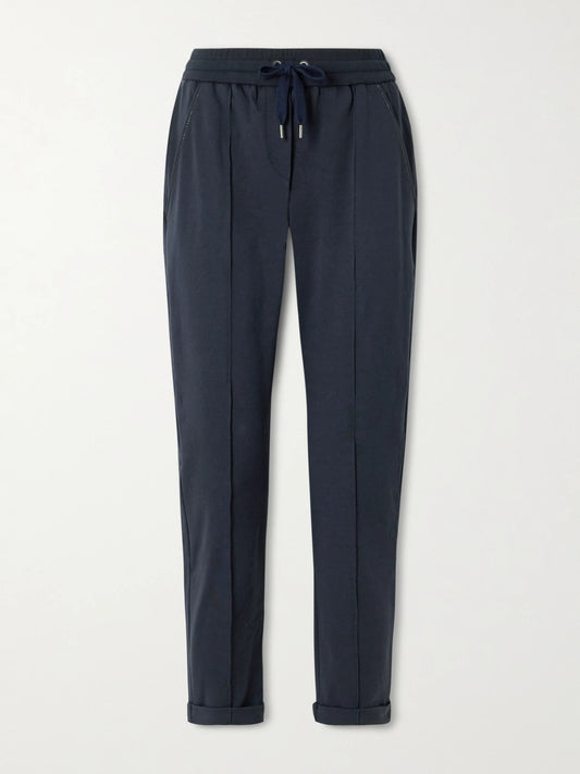 Image of a model wearing Tops. Product name - Bead-embellished Cotton-blend Jersey Track Pants in Navy colour by brand - Brunello Cucinelli
