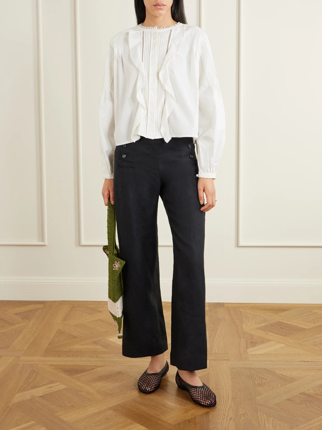 Image of a model wearing Pants. Product name - Sailor Cropped Linen High-rise Wide-leg Pants in Black colour by brand - BODE
