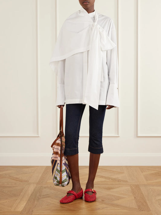 Image of a model wearing Tops. Product name - Clash Tie-detailed Asymmetric Cotton-poplin Shirt in Ivory colour by brand - Zimmermann