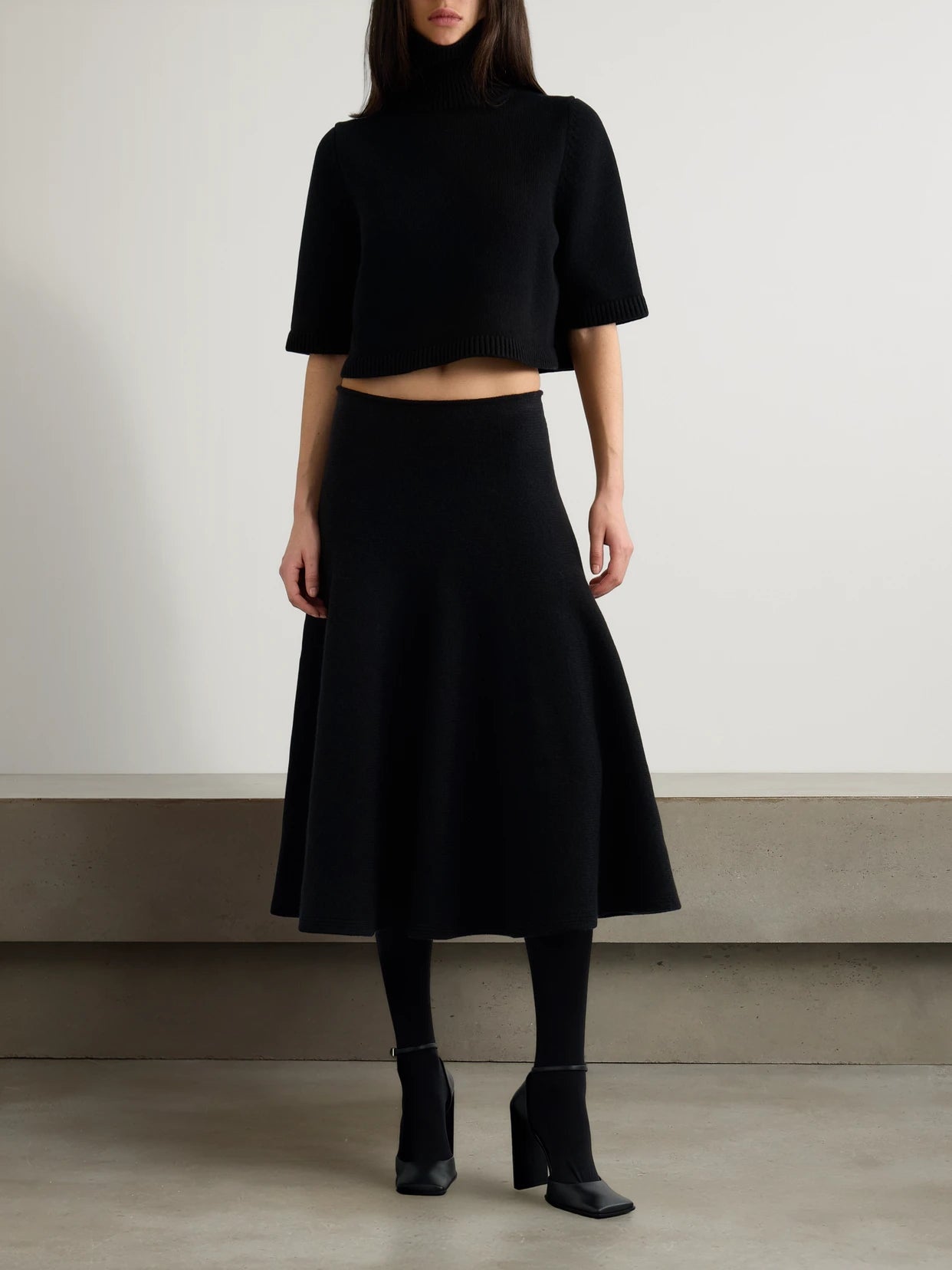 Image of a model wearing Skirts. Product name - Pleated Knitted Cashmere And Wool-blend Midi Skirt in Black colour by brand - Alaïa