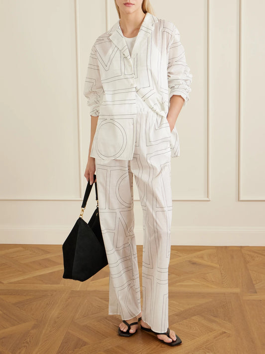 Image of a model wearing Pants. Product name - Embroidered Organic Cotton And Lyocell-blend Wide-leg Pants in White colour by brand - TOTEME