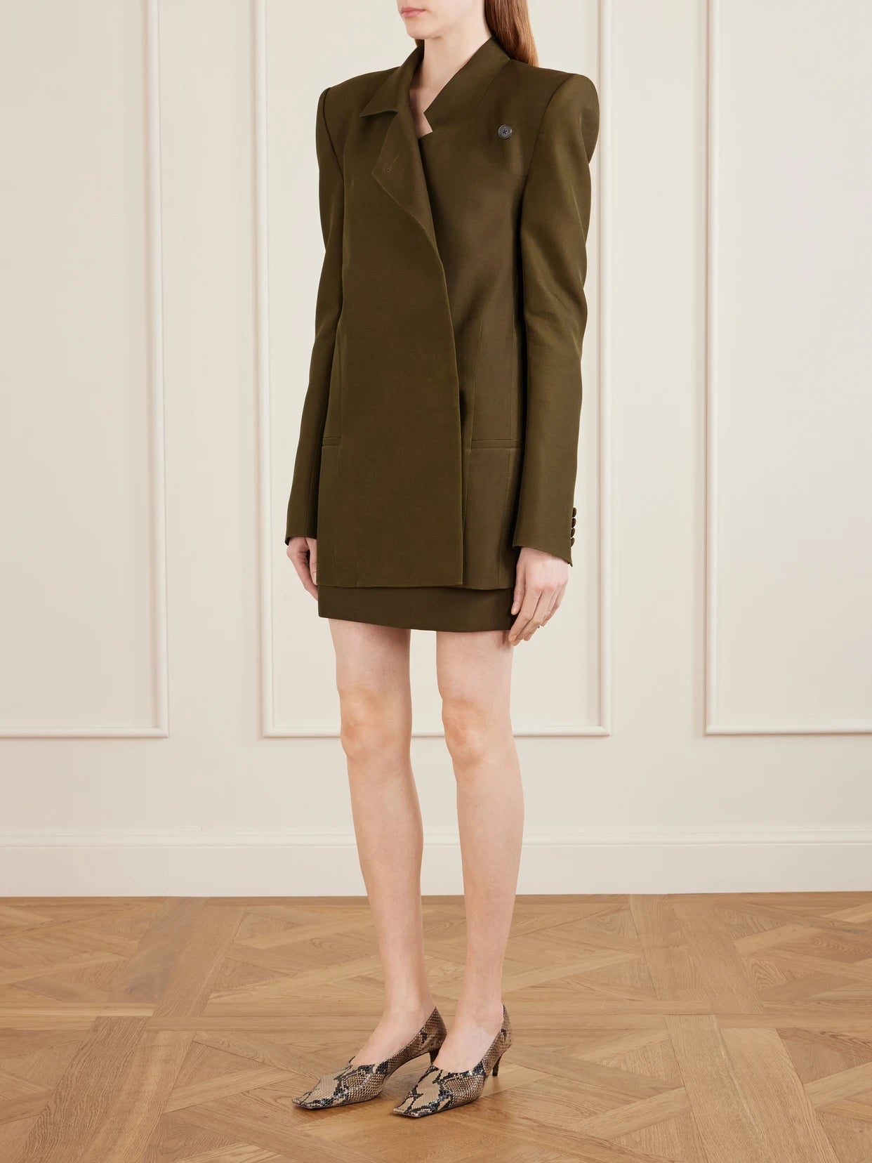 Image of a model wearing Skirts. Product name - Jett Wool And Silk-blend Cady Mini Skirt in Army green colour by brand - KHAITE