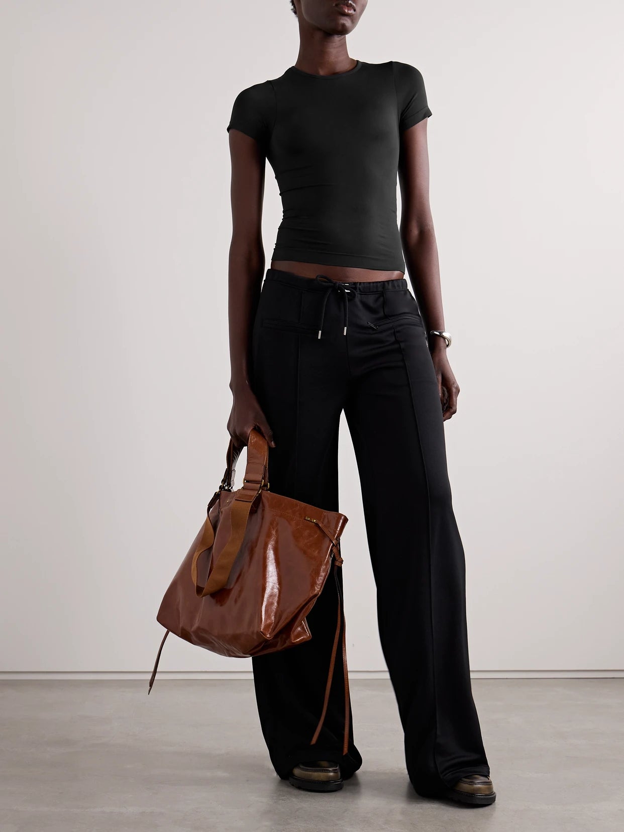 Image of a model wearing Tops. Product name - Soft Smoothing Seamless T-shirt - Eclipse in Black colour by brand - SKIMS