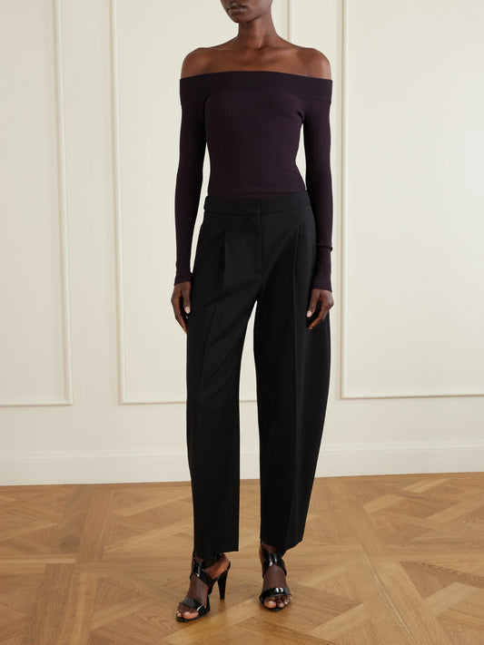 Image of a model wearing Pants. Product name - Pleated Wool-blend Gabardine Tapered Pants in Black colour by brand - Alaïa
