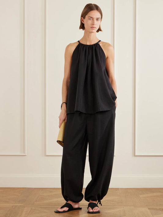 Image of a model wearing Tops. Product name - Gathered Lyocell-blend Halterneck Top in Black colour by brand - TOTEME