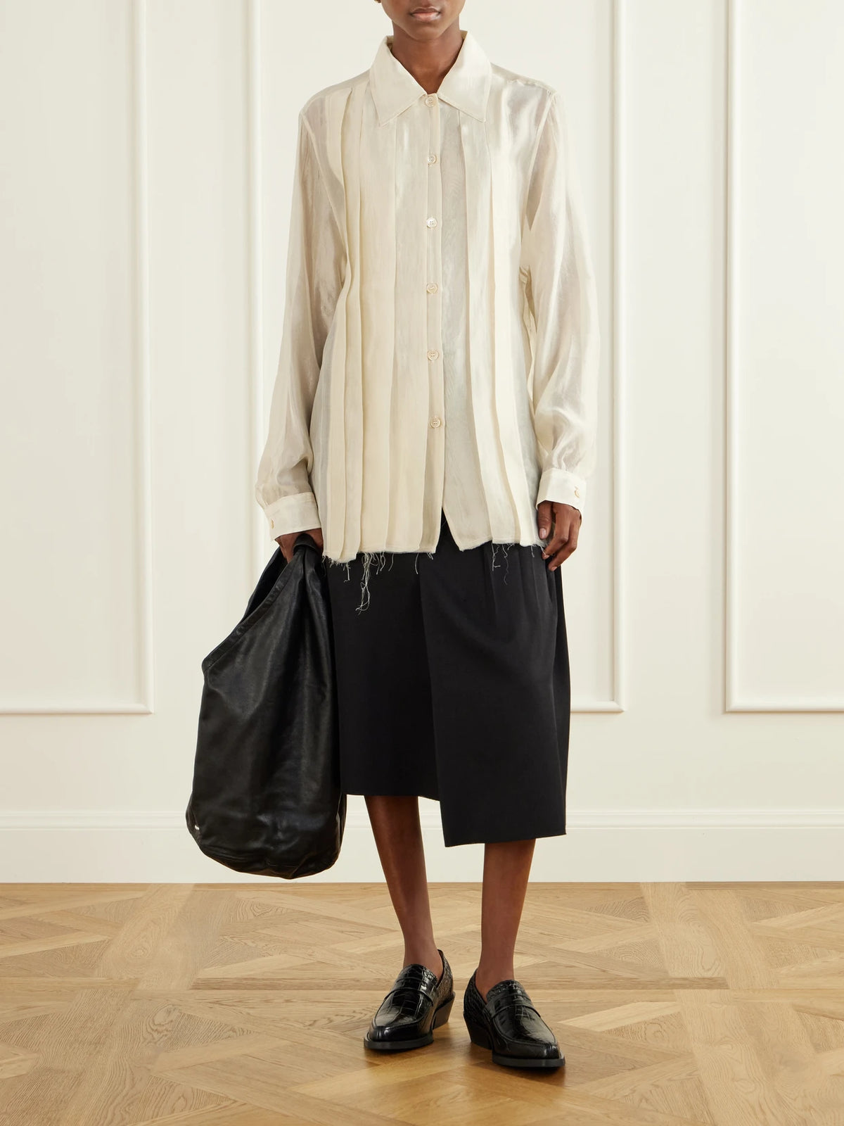 Image of a model wearing Skirts. Product name - Origami Asymmetric Pleated Virgin Wool Skirt in Black colour by brand - Our Legacy