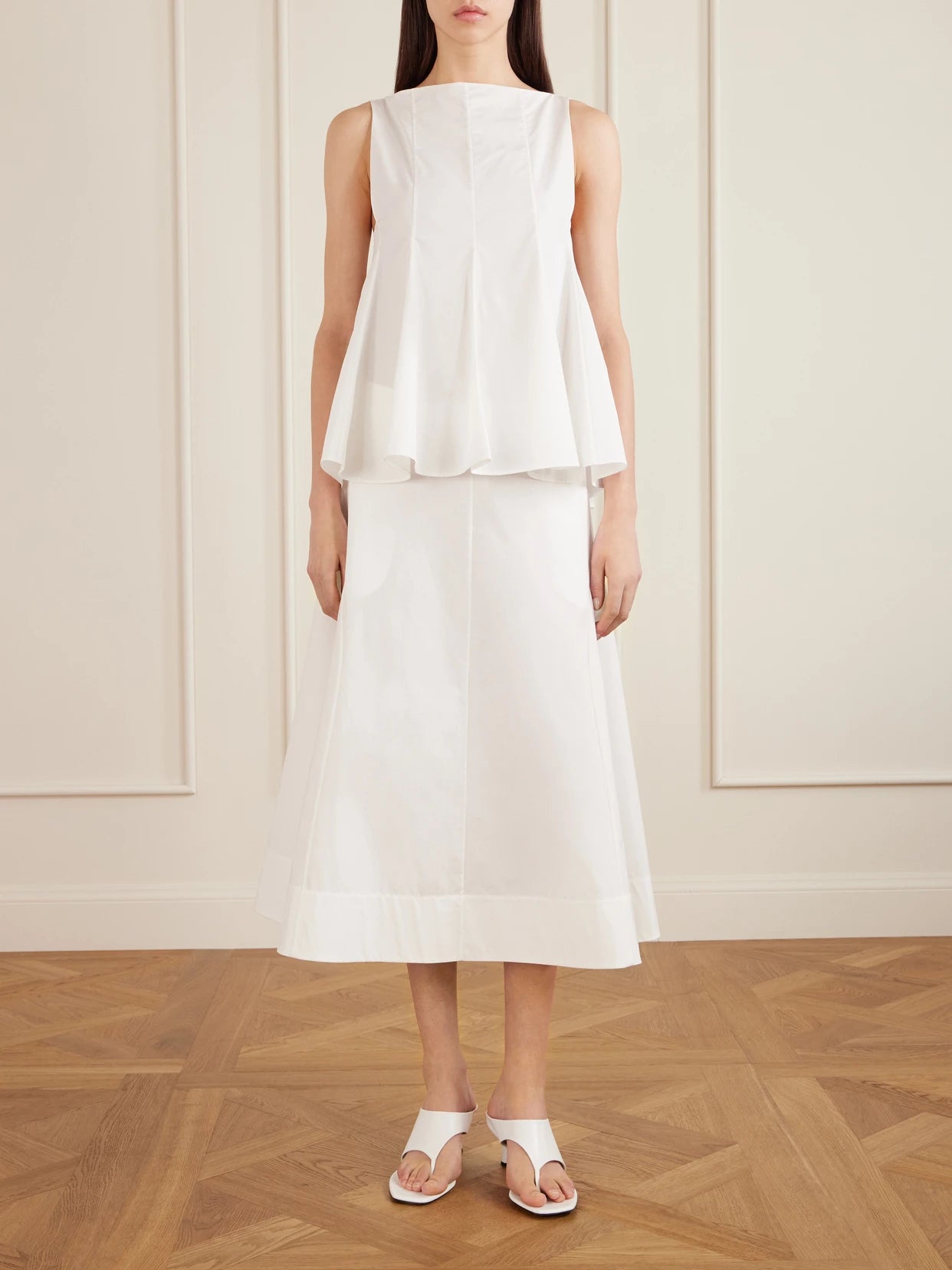 Image of a model wearing Skirts. Product name - Artin Paneled Cotton-poplin Midi Skirt in White colour by brand - KHAITE