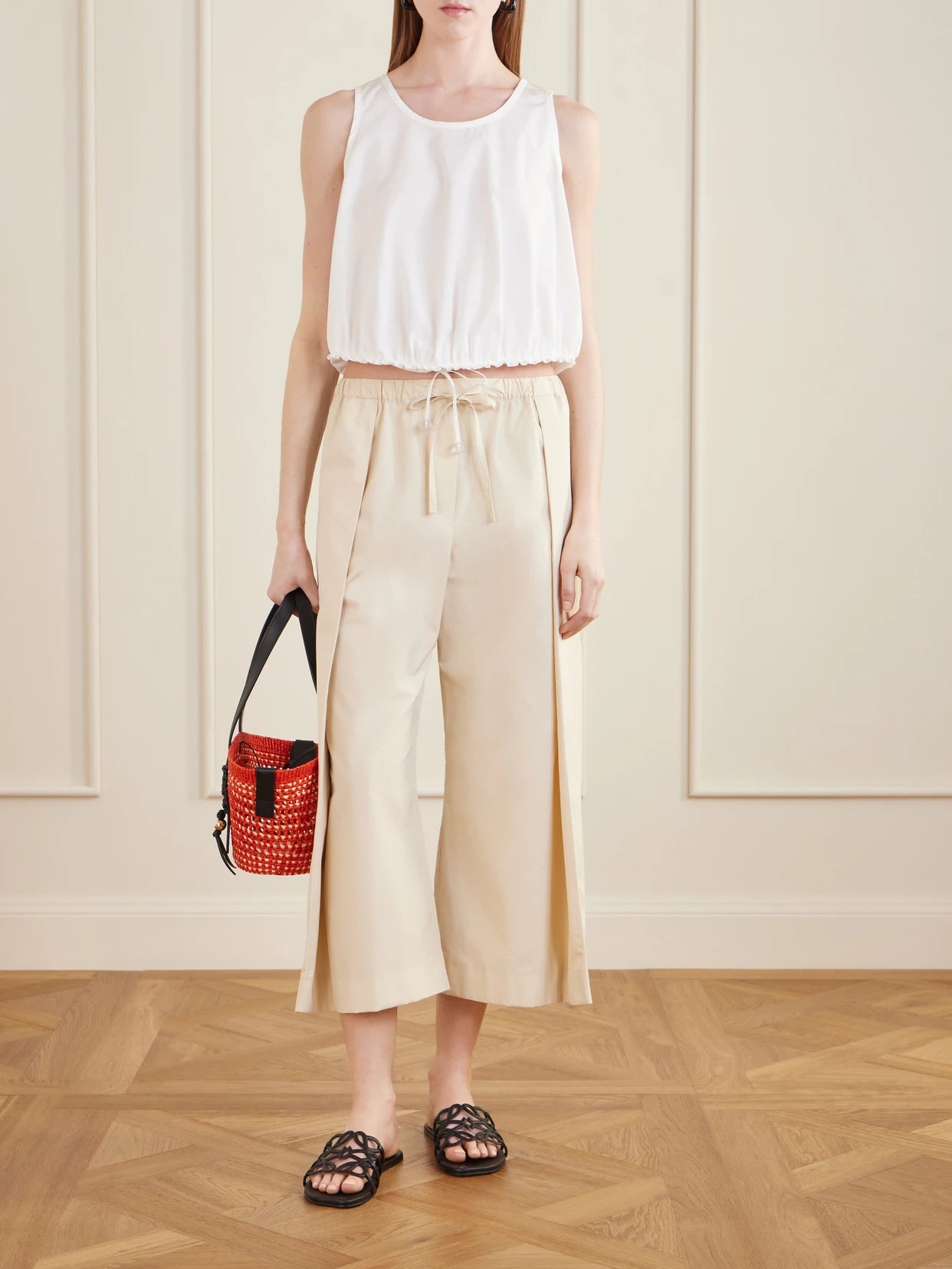 Image of a model wearing Pants. Product name - + Paula's Ibiza Pleated Cropped Cotton Wide-leg Pants in Beige colour by brand - LOEWE