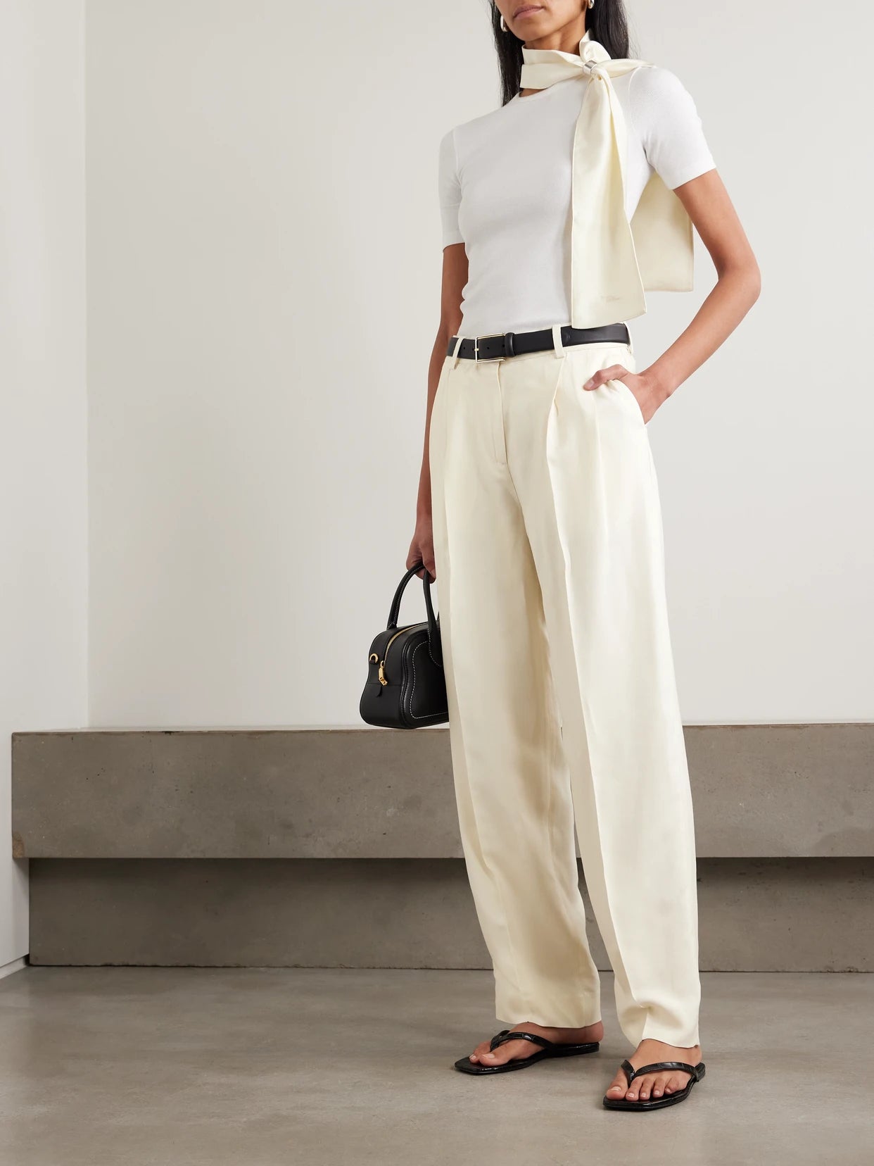 Image of a model wearing Pants. Product name - Garderob Pleated Woven Tapered Pants in Ecru colour by brand - TOTEME