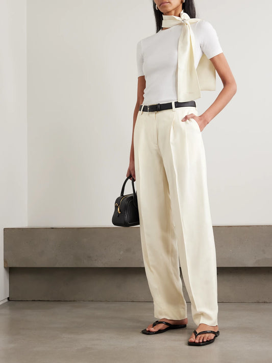 Image of a model wearing Pants. Product name - Garderob Pleated Woven Tapered Pants in Ecru colour by brand - TOTEME